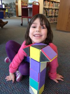 Girl plays with magnatiles in the library. 